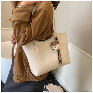 Detail of off-white tote bag with lychee grain leather texture and bear charm