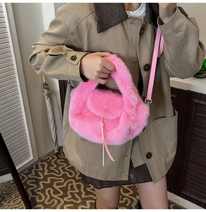 Detail der leuchtend rosa Kunstpelzhandtasche mit Lederriemen auf beigem Trenchcoat