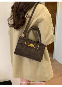 Detalle de bolso bandolera de ante marrón con hebilla de corazón dorado en gabardina beige