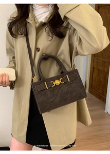 Detalle del pequeño bolso retro gris oscuro con herrajes dorados y textura de gamuza