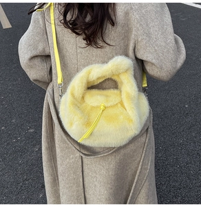Outdoor-Aufnahme der gelben Plüsch-Schultertasche mit modischem Knotengriff-Detail