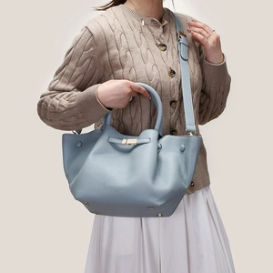 Detailed close-up of light blue textured leather tote with elegant pale gold metal hardware