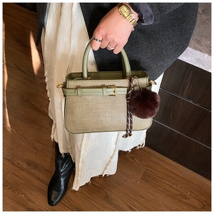 Detailed view of woven texture and smooth leather strap on a light green bucket bag