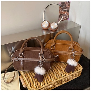 Détail des sacs Boston en daim café et caramel avec des breloques de gants en peluche douce