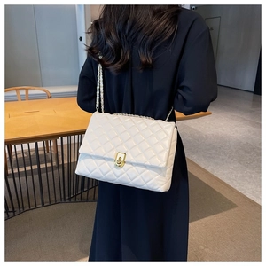 Rear view of model wearing white quilted crossbody bag with golden chain strap and flap