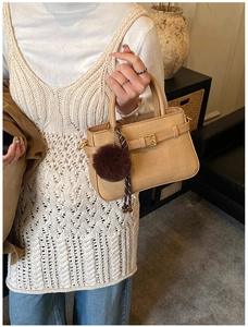 Close-up of khaki corduroy bucket bag with gold buckle and brown faux fur pompom