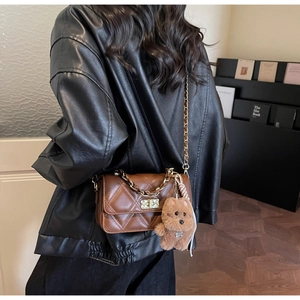 Close-up of brown quilted chain bag with gold hardware and plush puppy charm