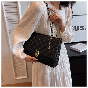 Close-up of black quilted leather texture and gold chain strap on shoulder bag