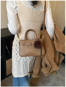Brown leather crossbody bag shown on model with plush charm and stylish gold buckle