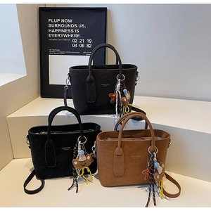 Trois sacs cabas élégants en daim noir, gris et marron sur des marches blanches