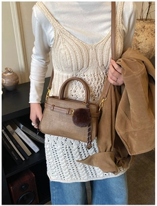 Vue détaillée d'un sac seau vintage marron foncé avec une breloque pompon en peluche