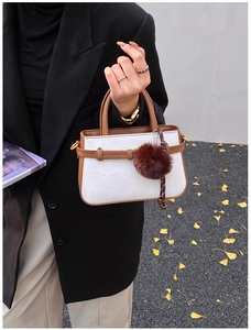 Detail of tweed mini bucket bag with leather trim and decorative brown plush ball charm