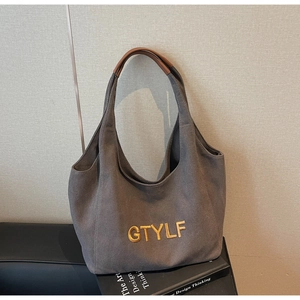 Detail of grey canvas tote bag with gold GTYLF embroidery and brown leather handles