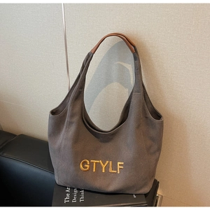 Detailed embroidery of yellow GTYLF letters on a grey canvas hobo bag with leather handles