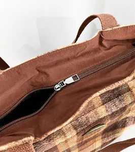 Detail view of the smooth metallic zipper and thick fabric lining on the plaid tote bag