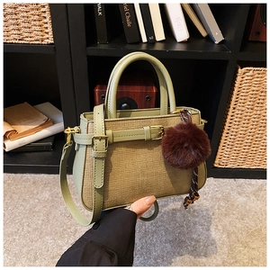 Detail of green leather and woven bucket bag with beads and brown plush ball charm