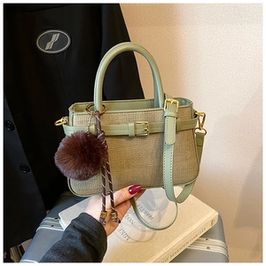 Detail of green leather and woven bucket bag with plush charm and gold hardware