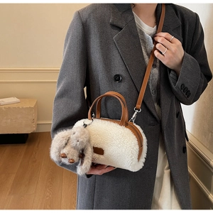 Detailansicht der weißen Plüschtasche mit braunem Lederriemen und Hasenanhänger