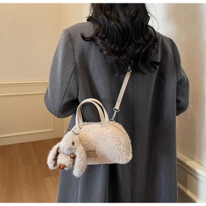 Detail der Plüschhandtasche in Off-White mit Hasen-Anhänger an einem grauen Blazer