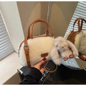 Detail der flauschigen Lammfell-Handtasche mit braunem Lederbesatz und Hasenanhänger