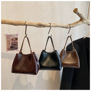 Drei minimalistische Eimertaschen aus glänzendem Kunstleder hängen an einem Ast im Shop