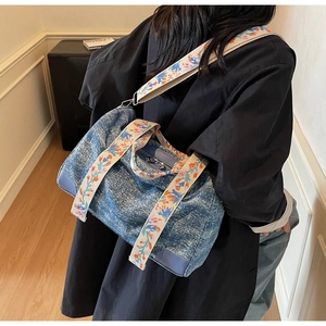 Detail of vintage denim tote bag with floral embroidered straps and leather corners
