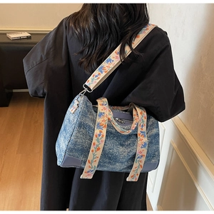 Detail of blue denim tote bag with colorful floral embroidery on the shoulder strap