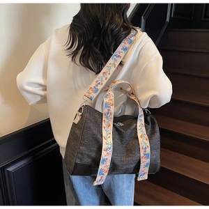 Detail view of the wide embroidered floral strap and reinforced leather corners on the tote bag