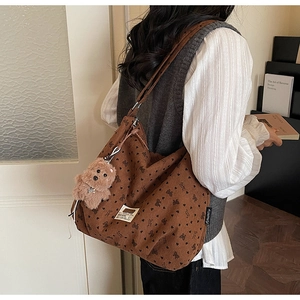 Detail van bruine corduroy tote tas met hart bloemenpatronen en pluche beer bedeltje