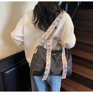 Deep grey canvas tote bag with colorful floral embroidery on the wide shoulder strap