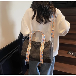 Detail of grey tote bag featuring colorful floral embroidery on the wide shoulder strap