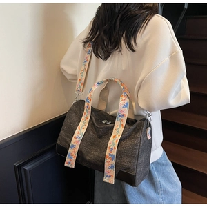 Detail of a charcoal canvas tote featuring a colorful bohemian floral embroidered strap