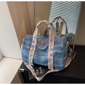 Detailed macro view of the dark denim Boston bag featuring ethnic floral embroidery handles