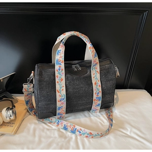 Detail view of black denim Boston bag featuring bohemian embroidered straps and leather logo