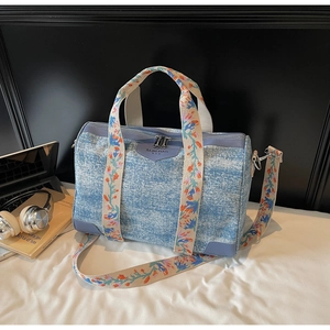 Detailed macro view of the blue denim textured Boston bag with floral embroidered strap
