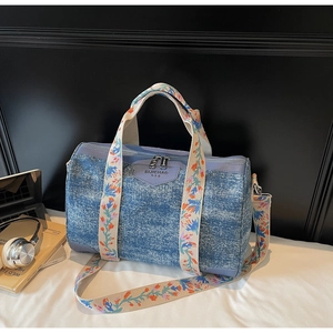 Detailed macro of vintage blue denim Boston bag featuring floral embroidered handles