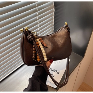 Detalle del bolso media luna de cuero marrón con cuentas de madera de colores y cierre dorado