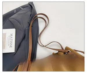 Detail of adjustable double straps on a brown leather tote bag with metal rings
