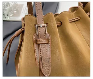 Macro shot of brown leather bucket bag with silver buckle and fine stitching details