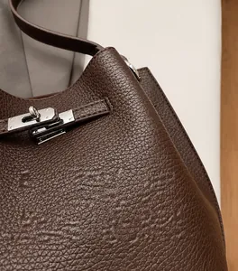 Close-up of dark brown lychee grain leather handbag with silver metallic turn-lock closure