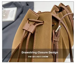 Close-up of brown pebbled faux leather bucket bag with drawstring and white stitching
