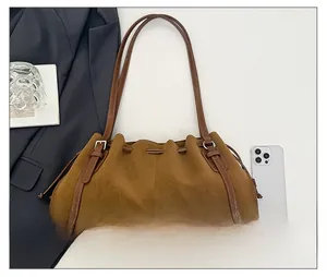 Flat lay of a brown suede hobo bag with drawstring detail and vintage aesthetics