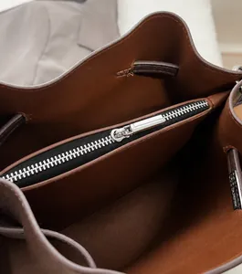 Close-up of premium smooth metal zipper and internal compartment on brown leather bag