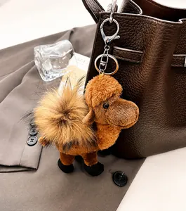 Plush camel-shaped bag charm with brown faux fur and silver hardware on a leather bag