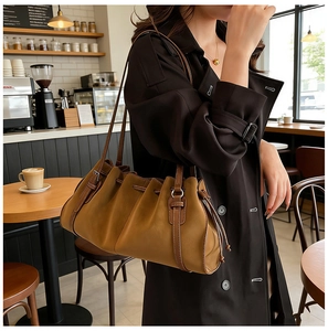 Detail of camel brown pleated leather tote bag with soft texture and slim shoulder straps