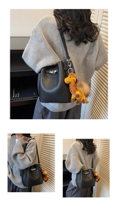 Detailed view of a black pebble leather bucket bag with metal lock and camel plush charm