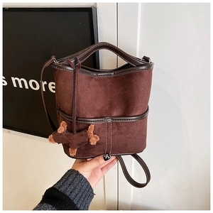 Detail of suede bucket bag in dark brown with contrast stitching and puppy charm