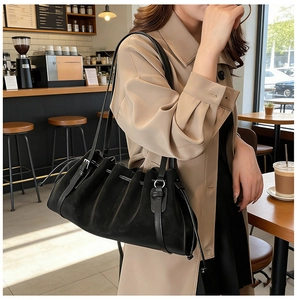 Detail of black pleated tote bag with matte texture and silver buckle strap accents