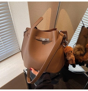 Detail of dark brown lychee leather bucket bag with silver twist lock and plush puppy charm
