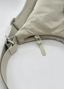 Dettaglio della cerniera e del nylon ripstop sulla borsa a tracolla beige spaziosa